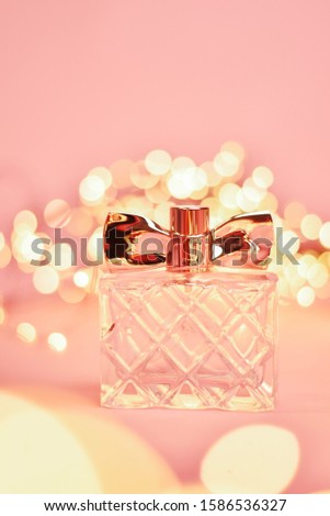 jar of perfume on a pink background with bokeh, garland, lights, composition.