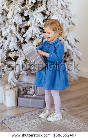 Little girl with Christmas gifts near a Christmas tree at home