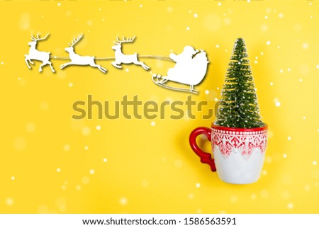Christmas tree in a holiday mug with snow, Santa and reindeers graphics