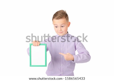 A joyful school boy holds a green frame.Boy smiles and shows to frame .An empty frame with a white background, space for your text.Isolated on white background.