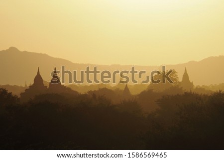 Beautiful silhouette view of the old Buddhist temples and Pagodas during sunset time with mountain background. Warm golden moment in ancient period for background and landscape view in Bagan Myanmar