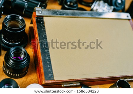 Retro mockup. Closeup old equipment for cut fotographic paper in center of retro vintage photographic accessories and quipments around on wooden Background. Side view