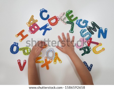 A kid arranges the alphabet wooden block set.