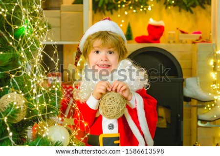 Christmas Carols. Happy boy holds a Christmas tree toy. Little cute santa claus. Christmas holiday for children.
