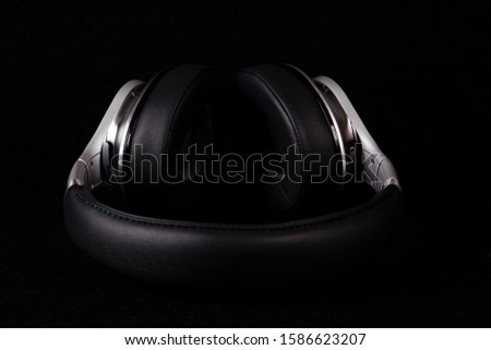 Black silver headphones lays on black background.