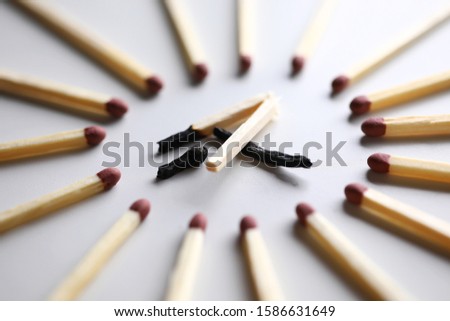 Broken burned out match in surrounded by evil intact fellows close-up. Dominance and cruelty among people concept Royalty-Free Stock Photo #1586631649