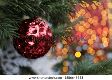 Christmas decorations on a fir branches on festive lights background, night illumination. New Year tree with toy balls, magic of a holiday for background