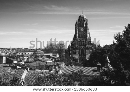 Saintes, Charente-Maritime, France. View of old city tiled roofs with Cathedral Saint-Pierre surrounded by trees at background. European architecture and heritage. Black white historic photo.