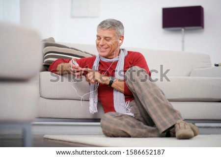 Happy senior man listening to at home