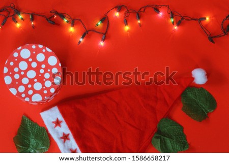 Christmas sparkling Santa Claus hat on red background. And gift box