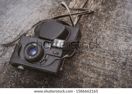 Retro black camera lying on the wooden background with a small amount of snow