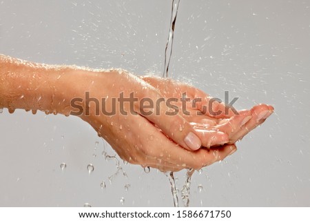 A stream of water splashing onto a woman's hands