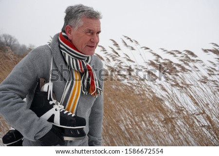 Senior man carrying ice skates on winter day