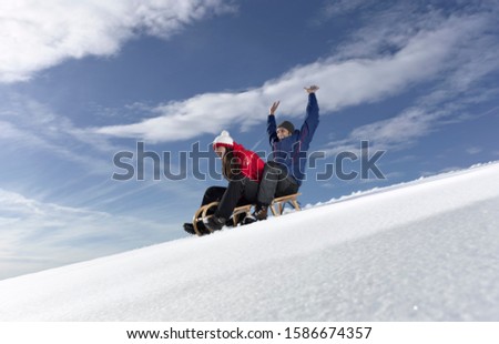 Mid adult couple snow sledding on snow slope