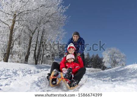 Young family sledding on winter day