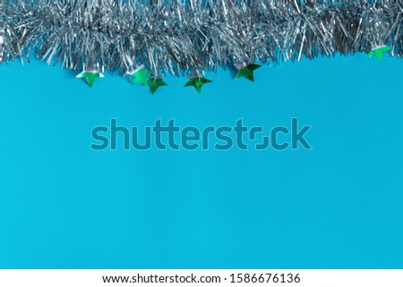 Silver shiny Christmas decorations, spruce branch, balls for the Christmas tree, bows, tinsel on a blue background, top view.
