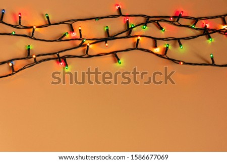Colorful Christmas garland lights on an orange background. Christmas light with copyspace for new year frame or christmas layout. Christmas decorations showcases
