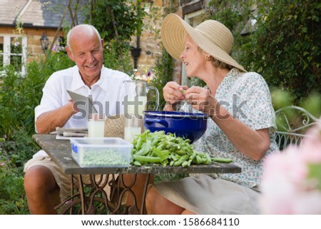Senior Couple Relaxing On Patio Outside Cottage