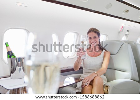 Attractive woman sitting and holding champagne glass in private jet Royalty-Free Stock Photo #1586688862