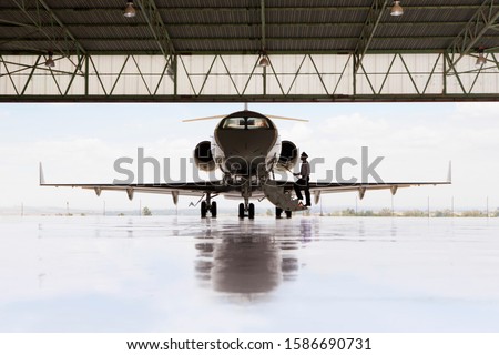 Silhouette of pilot boarding private jet in hangar Royalty-Free Stock Photo #1586690731