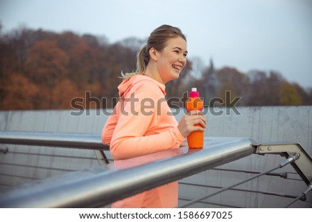 Joyful sporty lady holding bottle of water and laughing stock photo