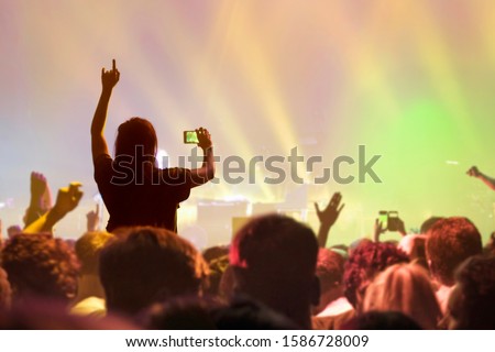 Music Fan Taking Picture On Mobile Phone At Rock Concert