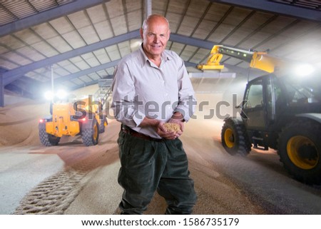 Portrait Of Farmer Inspecting Wheat Crop In Grain Store