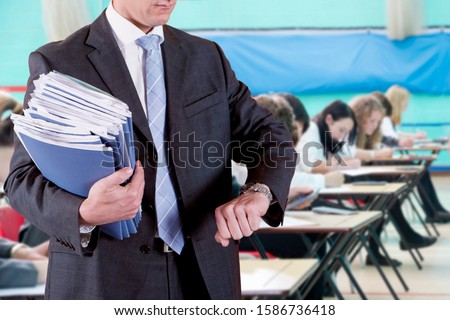 Close Up Of Teacher Supervising School Examination Royalty-Free Stock Photo #1586736418
