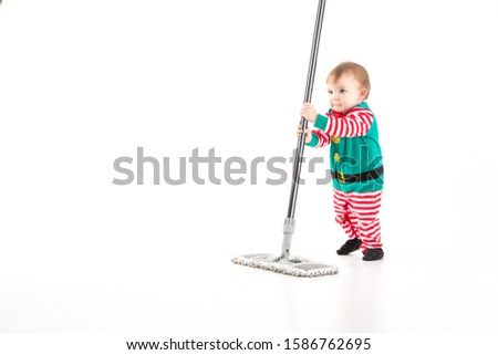 Stock studio photo with white background of a baby disguised as a elf playing with a mop