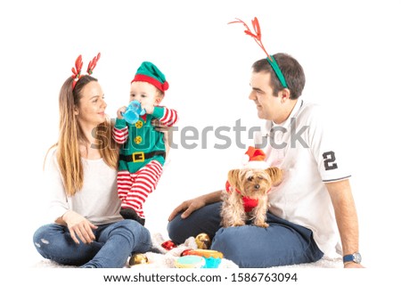 Stock studio photo of a couple with a baby drinking and a dog sitting on the floor disguised as Christmas with a white background