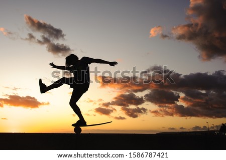 Silhouette of a skilled guy on balance board on a sea shore