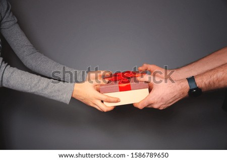 Males hands give a present with red ribbon. Valentines gift, place for text.