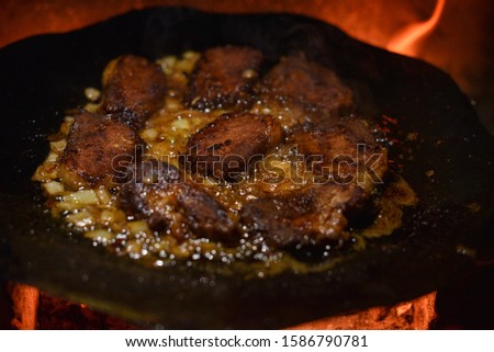 Cutlets pan fried in the fire. pan is also cooking meat. Pork chunks of meat are cooked on a bonfire on a disc from a harrow. Chunks of meat are fried with onions. Tasty dinner or lunch. Street food