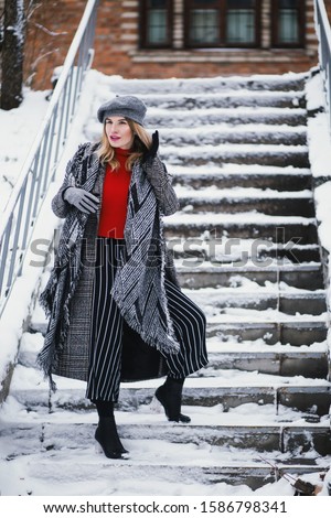 An attractive happy female in warm winter clothing on a snowy staircase
