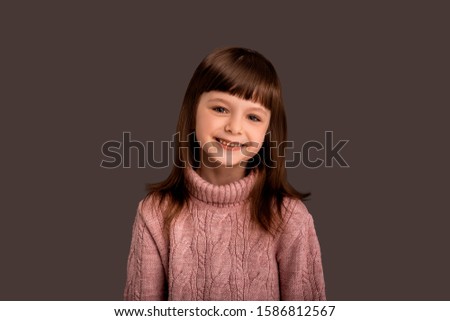 Happy smiling pretty child girl in pink sweater over gray background. Active beautiful childhood time, happy expression. Little kid caucasian model, cute, charming face. Baby face. Lifestyle concept.
