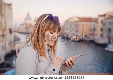 Young beautiful girl uses map phone navigator on canal background in Venice Italy. Trip concept.