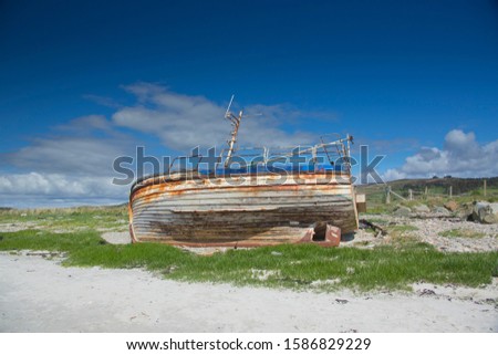 Derelict wooden fishing boat abandoned on pristine and peaceful white sand atlantic beach at Tayinloan on the Kintyre peninsula on the west coast of Scotland 