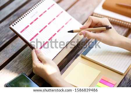 Woman planning agenda and schedule using calendar event planner, Writing plan on memo note. Planner of meeting plan job this year.                               