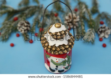 Christmas composition lantern snowman on the blue background of a winter spruce. Close-up. The concept of Christmas and New Year. Card.