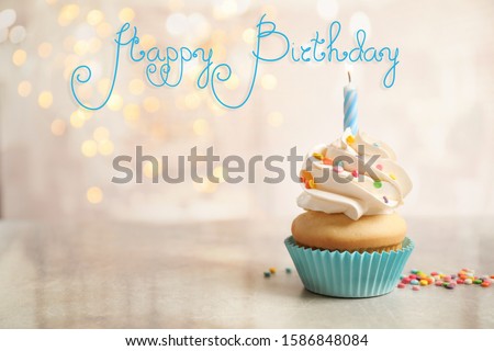 Delicious cupcake with candle on light table against blurred lights. Happy Birthday