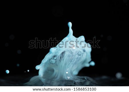 Baby blue colored milk splashes into water and is frozen in space with high speed photography