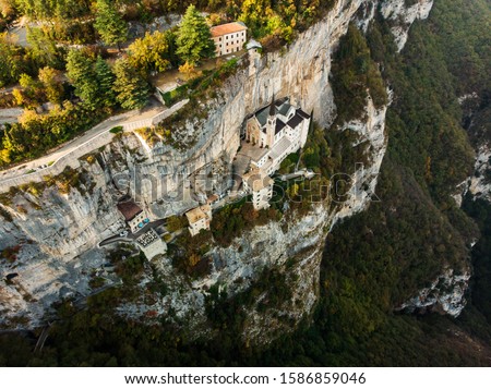 The famous and unique Church in the rock Madonna della Corona on Monte Baldo in Italy near Verona, a place of pilgrimage for many Catholics, aerial panorama from a drone to the Abbey built on the rock