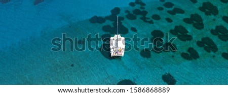 Aerial drone ultra wide photo of luxury sail boat with wooden deck docked in tropical exotic island with turquoise sea