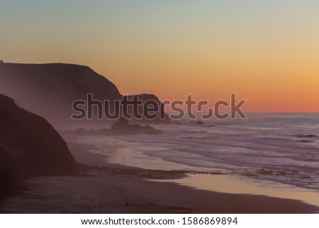 A beautiful picture of the sea covered in fog surrounded by rocks during sunset in Portugal, Algarve