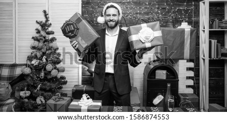 Gifts for colleagues. Which one is mine. Man bearded businessman wear suit santa hat hold gift boxes. Christmas gifts. Man prepared gifts for everyone. Spread happiness and joy. Generosity concept.