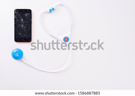Modern mobile smartphone with a broken screen with a children's fanendoscope isolated on a white background. View from above.