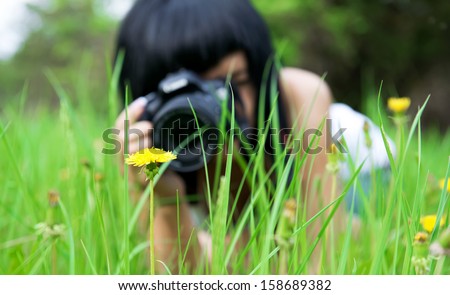 young girl taking picture of  dandelion in nature