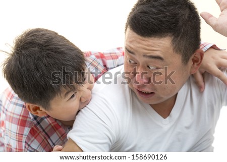 Asian son biting father shoulder while playing on isolated white background