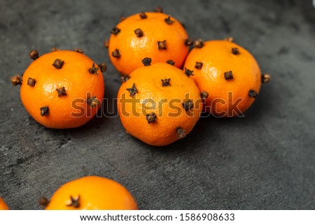 tangerines decorated with a whole clove on a dark gray table. christmas decorations