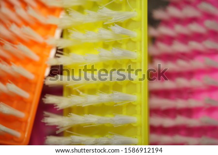 Abstract background image, three colorful plastic brushes, macro photo. The motley bright multi-colored image is orange, yellow and pink.